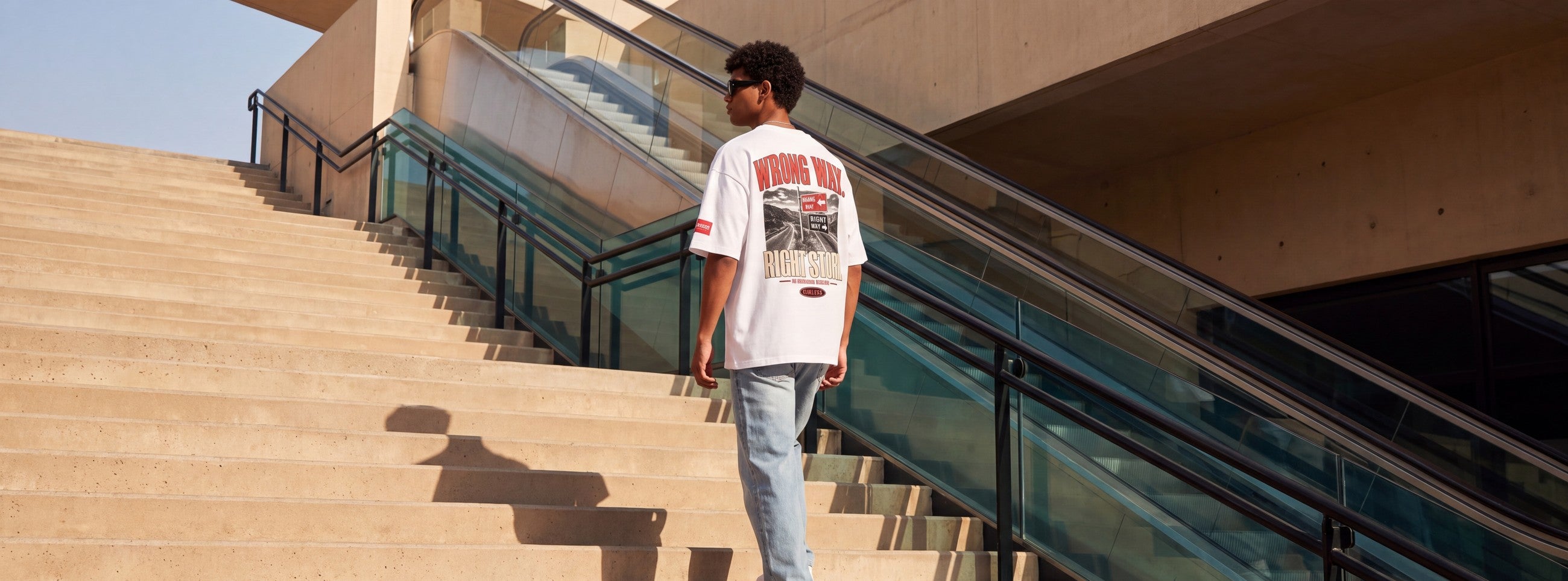 Wrong Way oversized tee, back print, on a concrete staircase